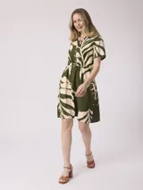 Vestido corto con estampado de hojas color verde y beige, con cuello camisero, mangas cortas y cintura elastizada.