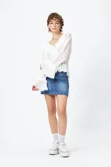 Blusa blanca de gasa con escote en V y volados en el cuello y las mangas largas. Se ata con lazos finos al frente.