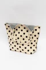 Bolso tipo tote de tejido de punto color crema con lunares negros. Interior con forro de tejido de punto a rayas blancas y negras.