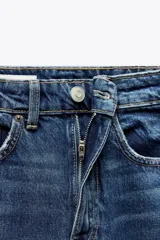 Pantalón de jean negro de tiro alto, corte recto, con cinco bolsillos y cierre frontal con cremallera y botón metálico.