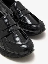 Mocasín New Balance 1906L negro con textura de piel de cocodrilo, suela acolchada 860v2 y almohadillas ABZORB SBS segmentadas en el talón.