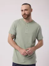 Remera azul de algodón con cuello redondo y tapeta con botones.