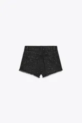 Short de jean negro con lavado gastado y pequeñas estrellas blancas estampadas. Tiene tiro alto, corte recto y terminación desflecada.