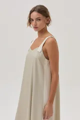 Vestido largo color beige de lino metalizado, con tirantes anchos a contratono y corte recto con abertura lateral.