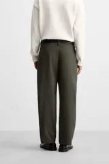 Pantalón verde oliva de corte amplio con pliegues en la parte delantera, bolsillos laterales y traseros de ojal.