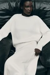 Sweater color blanco de punto perlado, con cuello redondo y mangas largas.