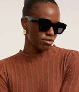 Suéter negro de punto con cuello redondo y mangas largas. Presenta rayas verticales texturizadas y tejido con hilos metalizados.