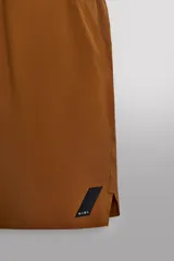 Pantalón corto deportivo color marrón oliva, con cintura elástica ajustable con cordón, bolsillos frontales y bolsillo trasero con cierre. Presenta forro interior y detalle de logo estampado en la pernera.