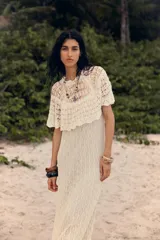 Vestido largo color crudo, tejido a crochet con diseño calado. Tiene cuello redondo, mangas cortas con volados y forro interior.