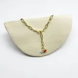 Cadena dorada de acero con eslabones grandes. Tiene cierre de mosquetón y dijes colgantes de coral rojo y aguamarina celeste.