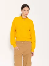 Sweater amarillo de tejido cerrado, mangas largas y largo a la primera cadera. Es de cuello redondo cerrado.