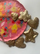 Collar dorado con cadena y dijes colgantes con formas de corazón, estrella y flor.