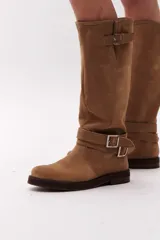 Bota de caña alta color negro, confeccionada en gamuza, con dos correas desmontables con hebillas metálicas.