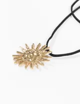 Collar con cordón negro ajustable y dije dorado con forma de sol texturizado.