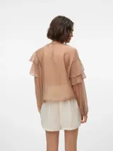 Blusa color beige con volados, cuello redondo y mangas largas abullonadas con puños abotonados.