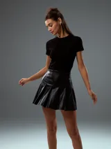 Minifalda negra de cuero sintético con diseño plisado.