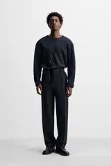 Pantalón de vestir negro de corte recto, con cintura elástica, pliegues frontales, bolsillos laterales y traseros.
