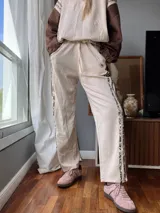 Pantalón de jogging color crema con cintura elastizada y cordón ajustable. Presenta una franja lateral con estampado animal print.