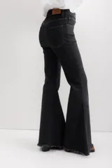 Pantalón de jean color crudo, de corte acampanado, tiro alto y terminación desflecada.