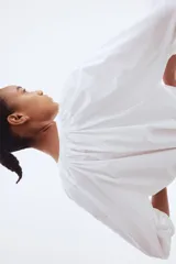 Blusa blanca de popelina de algodón con cuello mao, abertura en V y botones frontales. Mangas globo tres cuartos de corte raglán con puños finos y bajo recto.