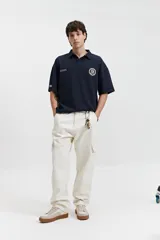 Polo azul marino con textura y corte oversize. Presenta un logo estampado en el pecho y mangas cortas.