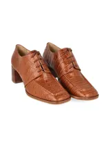 Zapato de vestir negro con textura símil piel de cocodrilo, cordones finos y tacón cuadrado.