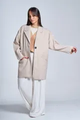 Tapado gris oscuro de corte oversize, con solapa clásica, hombros caídos, cierre con un botón central y bolsillos laterales funcionales.