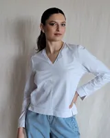 Remera blanca de mangas largas con cuello en V y costuras a la vista.