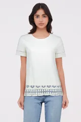 Remera holgada color marfil con detalles de encaje en el bajo y mangas cortas.