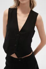 Chaleco negro sin mangas con cuello en V y cierre frontal con botones.