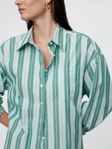 Camisa oversize a rayas verticales verdes y blancas, con cuello clásico, manga larga y bolsillo en el pecho.