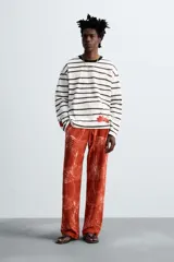 Pantalón relaxed fit de punto ligero tejido en hilatura de algodón color ladrillo con estampado a cuadros difuminados en blanco. Cintura elástica ajustable con cordón y bolsillos laterales.