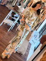 Blusa de satén con estampado de cadenas y hojas en tonos blanco, marrón y negro. Tiene corte amplio, mangas cortas y cuello redondo. Se ajusta a la cintura con un cinturón elástico negro con hebilla dorada.