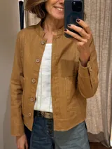 Chaqueta color caramelo de lino y algodón, con cuello mao, cierre frontal con botones de madera, bolsillos de parche y pespuntes a contraste.