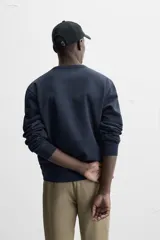 Sudadera negra de corte holgado, cuello redondo y mangas largas con puños acanalados.