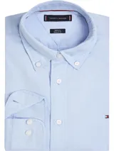 Camisa celeste de popelina de algodón con tecnología Flex, cuello abotonado, corte regular, puños en inglete con dos botones y logo de Tommy Hilfiger bordado en el pecho.