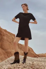 Vestido corto negro con cuello redondo, mangas cortas, flecos en el canesú y detalle de tachas plateadas.