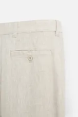 Pantalón de vestir blanco, confeccionado en lino, de corte recto, con bolsillos laterales y traseros. Se ajusta a la cintura con botón y cierre.