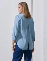 Camisa celeste de tencel con cuello con solapa, escote en V, abertura central con botones y mangas 3/4 regulables con presilla y botón.