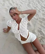 Conjunto de tejido crochet color blanco, compuesto por un cárdigan con botones y shorts.