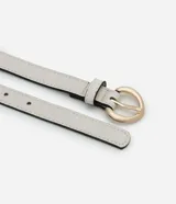 Set de tres cinturones finos de cuero sintético con hebilla redonda dorada: uno color beige, uno color blanco y uno color negro.