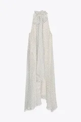Vestido largo de cuello halter con lazadas ajustables y estampado de lunares negros sobre fondo blanco. Tiene bajo asimétrico, forro interior y cierre con abertura y botón en la espalda.