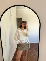 Blusa color crudo calada de crochet, de mangas largas y cuello redondo.