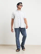 Camisa de manga corta a rayas verticales celestes y blancas, con cuello clásico y botones marrones.