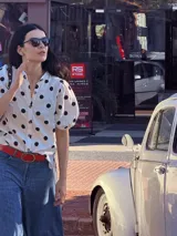 Camisa blanca de muselina con estampado de lunares negros, manga corta abullonada y botones al frente.