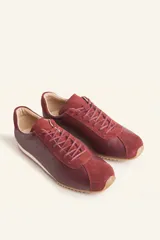Zapatillas deportivas de cuero color borgoña con detalles en gamuza al tono, cordones finos y suela de goma blanca.