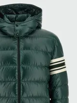 Campera puffer verde oscuro con capucha, cierre frontal con cremallera, bolsillos laterales con cremallera y detalle de rayas blancas en la manga izquierda.