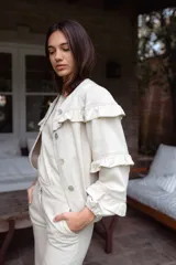 Campera de jean gris oscuro con volados en el frente y las mangas, de corte recto y largo a la cadera.