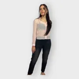 Camisa rosa pálido de tela transparente con textura y pequeños tajos en los costados. Tiene cuello clásico, mangas largas con puños abotonados y cierre frontal con botones.