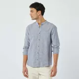Camisa celeste de lino con cuello mao, manga larga con puños abotonados, cierre frontal con botones y bolsillo de parche en el pecho.